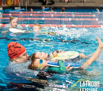 Swimming instructor helping child swim