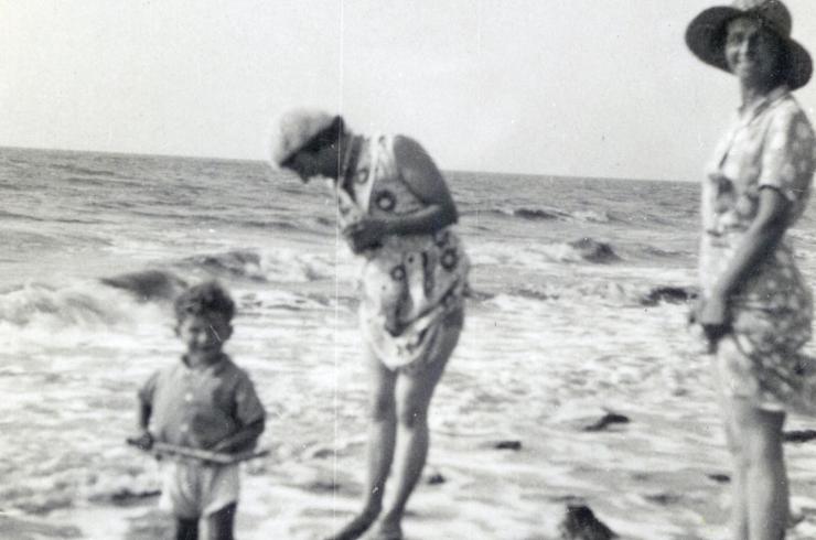 Black and white historical photo of two woman and a young child paddling in the sea