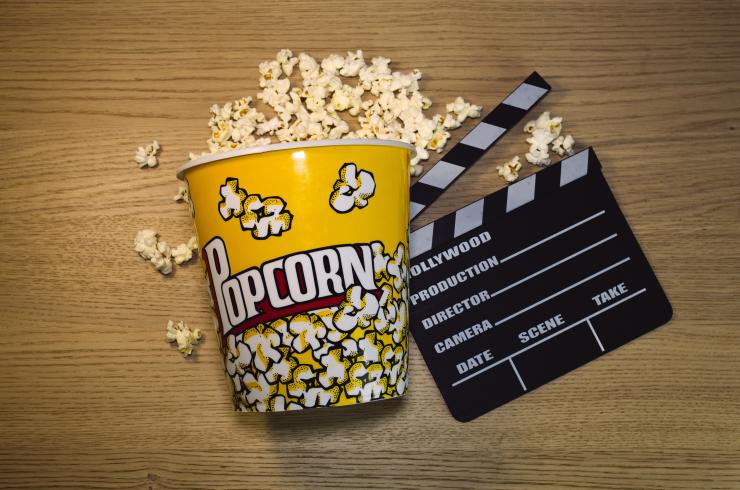 Image of popcorn and a clapper board on a wooden surface.