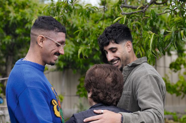 Image showing Daniel and Luke Mancuso from social enterprise Yiayia Next Door embracing an older woman in a garden
