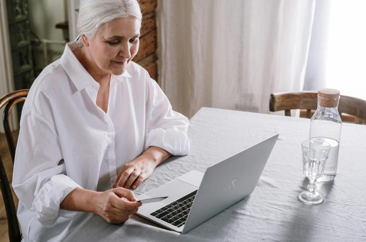 Older woman in a white shirt looking at a laptop