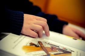 Colour image of a child's hand reading from a picture book