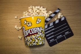 Image of popcorn and a clapper board on a wooden surface.