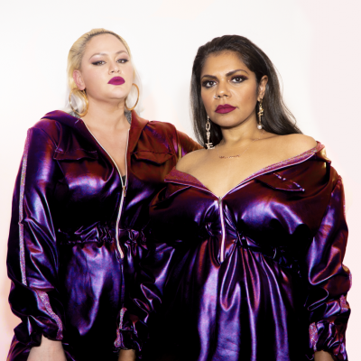 Two indigenous women dressed metallic purple clothing